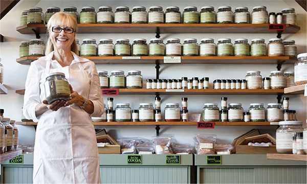 lady holding jar in front a business display of jars