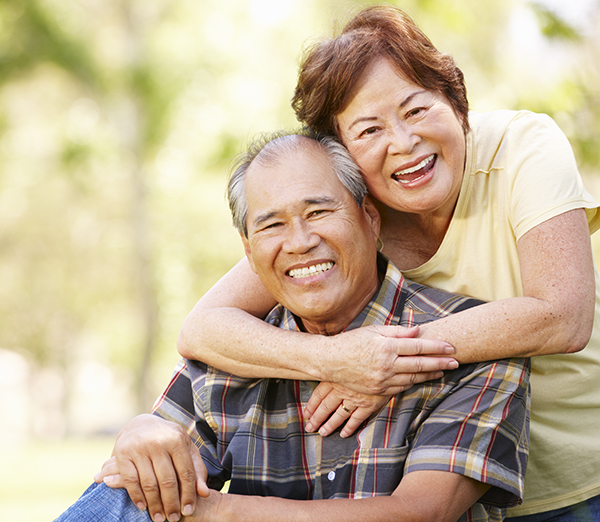 woman embracing man from behind with her arms around his shoulders